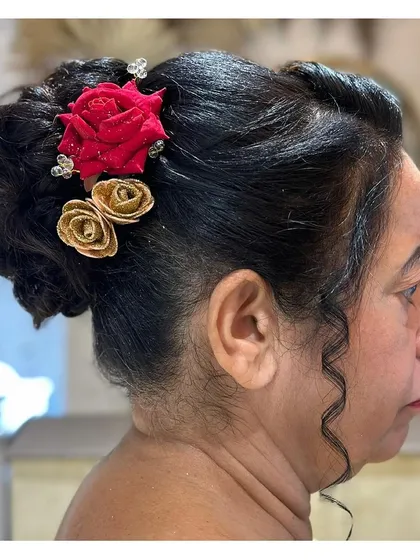 A traditional bun hairstyle adorned with artificial red and gold roses. This is a classic choice for weddings and festive events.