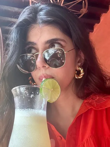 Another look at Sanjana Sanghi enjoying a drink while wearing our braided beauty hoops. They are the perfect accessory for a stylish day out.
