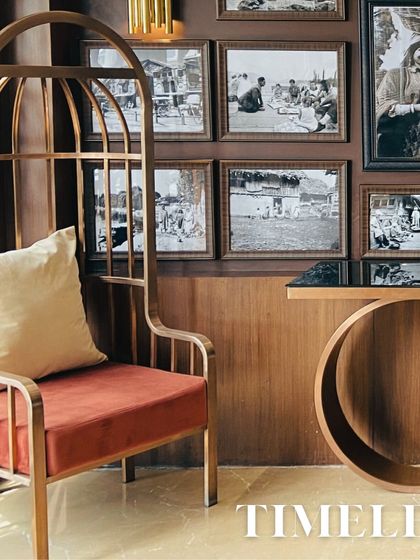 This image showcases a timeless furniture piece, a high-backed accent chair with a birdcage-like frame. It's set against a gallery wall of black-and-white photos, blending classic elegance with modern design.