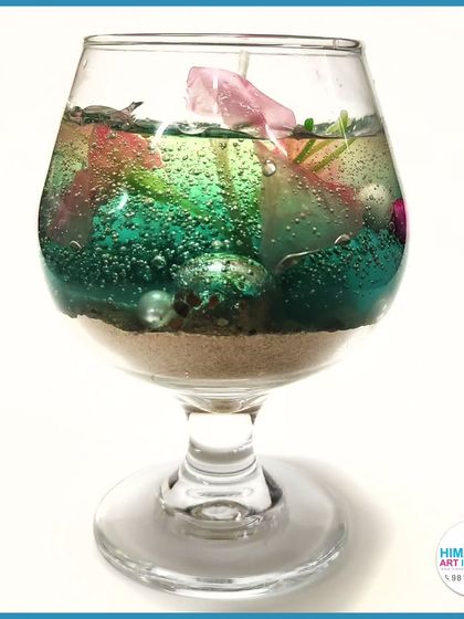 A colorful gel candle in a wine glass, filled with decorative elements. We show you how to use various containers for your candle creations.