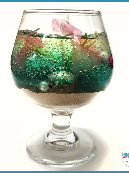 A colorful gel candle in a wine glass, filled with decorative elements. We show you how to use various containers for your candle creations.