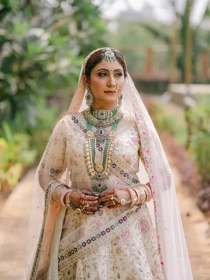 A classic bridal portrait. The bride looks poised and elegant, with her makeup and styling perfectly complementing her intricate outfit and jewelry.