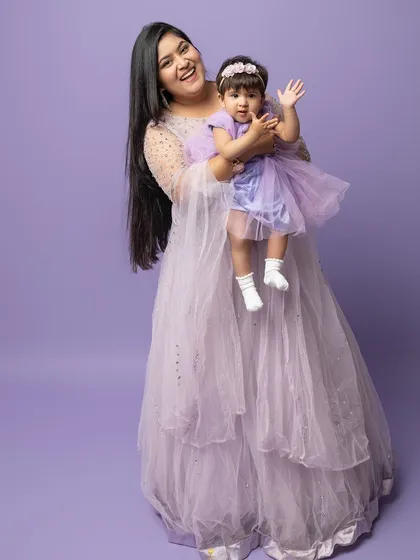 A mother and her daughter share a happy moment. The coordinating lavender dresses add a soft, dreamy feel to this lovely portrait.