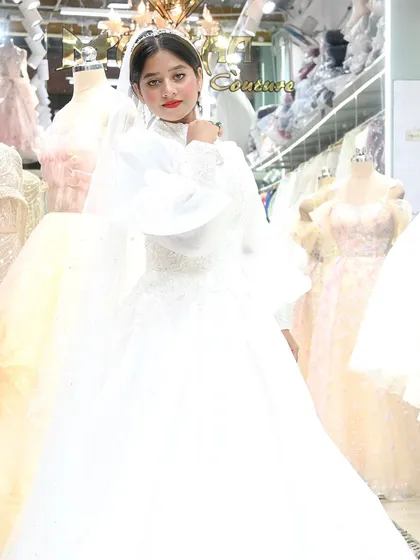 A stunning bride in a classic white gown with dramatic bishop sleeves and a high neckline. This look is a perfect example of timeless elegance with a modern flair.
