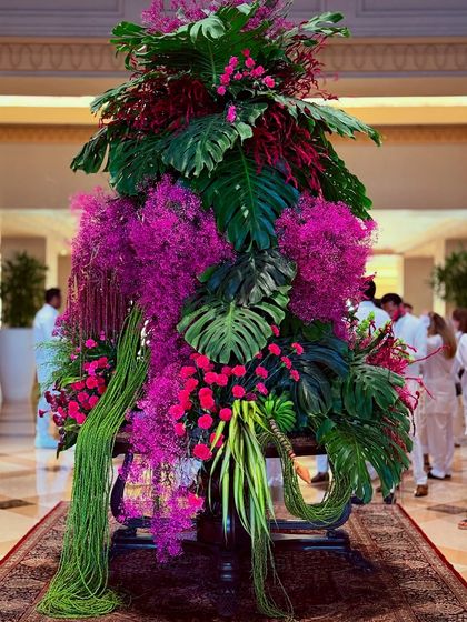 A vision in pink and green. This tropical-themed lobby installation is a celebration of vibrant color, featuring massive monstera leaves, cascading green amaranthus, and explosive bursts of pink florals. It’s designed to transport you to a lush paradise.