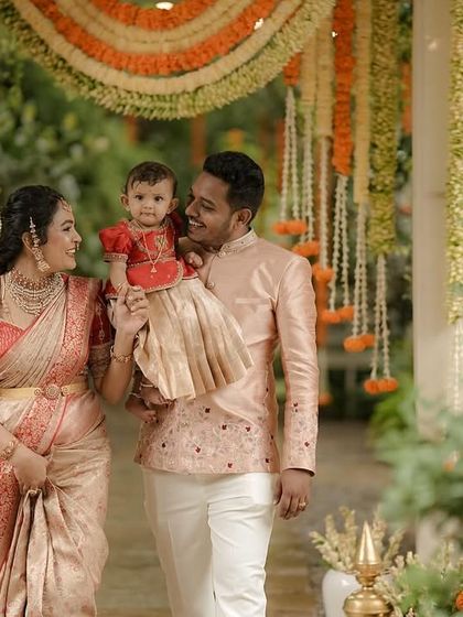 A family walks together under a floral archway, dressed in our coordinated designs. The soft peach and red tones of their outfits create a warm and unified aesthetic for their special day.
