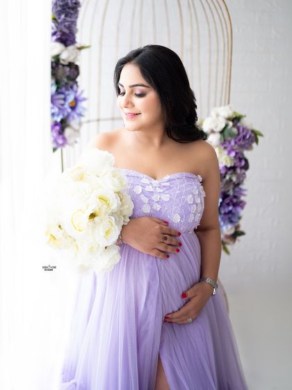 A beautiful window-lit portrait in a lovely lavender gown. The floral-adorned birdcage prop adds a touch of whimsical charm.