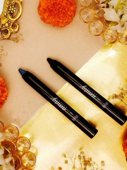 A festive flatlay featuring eye pencils surrounded by marigold flowers and decorative gold elements. The warm, vibrant colors are perfect for a Diwali-themed beauty campaign.