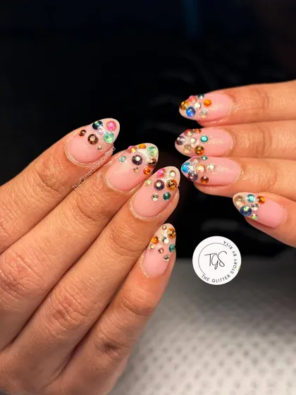A playful design with multi-colored rhinestones scattered across the tips of these almond-shaped nails for a fun, confetti-like effect.