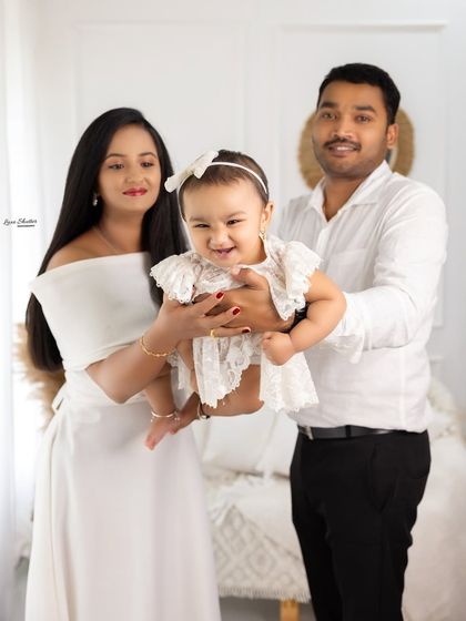 A happy family portrait with the parents holding their giggling daughter. Her joyful expression is the heart of this beautiful photo.