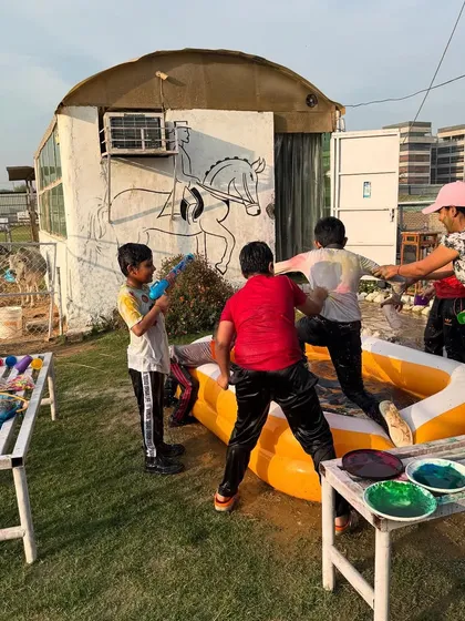 Kids playing with colors and water guns next to the pool, with our rustic buildings in the background.
