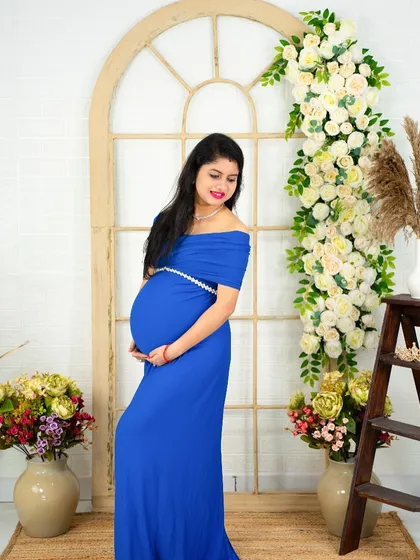 A classic maternity pose in a royal blue gown. The mom-to-be stands against our floral archway, creating a timeless and beautiful portrait.