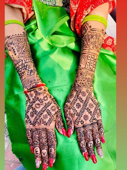 A personalized bridal design with the groom's name "Devender" written on the fingers. This is a popular request for Karva Chauth and weddings.
