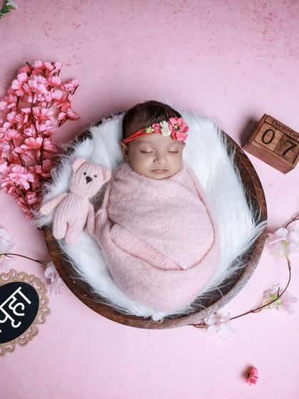 A beautiful pink-themed setup with a baby in a bowl, surrounded by cherry blossoms and a personalized nameplate. We can add custom elements to your session.