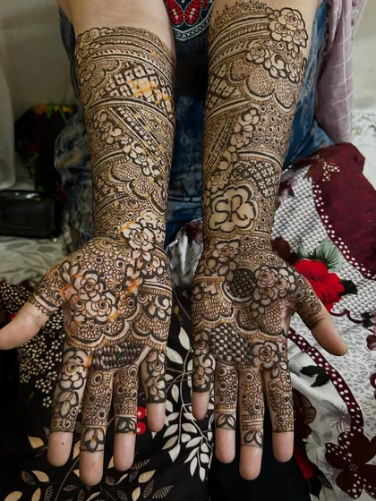 A personalized bridal design featuring the initials 'SR' cleverly hidden within the floral patterns on the palm. The rest of the design is packed with fine details and traditional motifs.