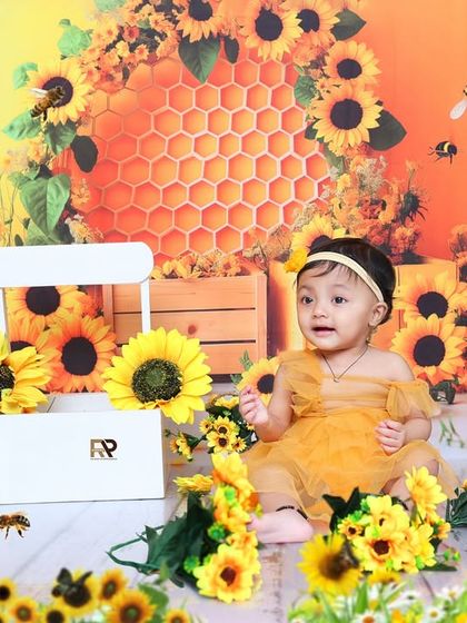 A baby girl explores the sunflower-themed set, surrounded by golden flowers and honeycombs. This theme is perfect for celebrating your little sunshine.