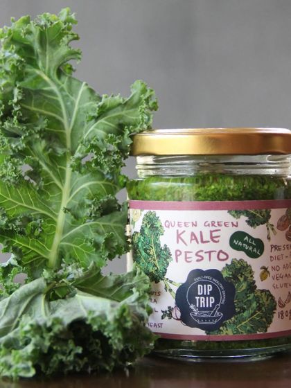 A jar of my Queen Green Kale Pesto next to a fresh kale leaf. This visual connection shows my commitment to using fresh, high-quality ingredients in every product.