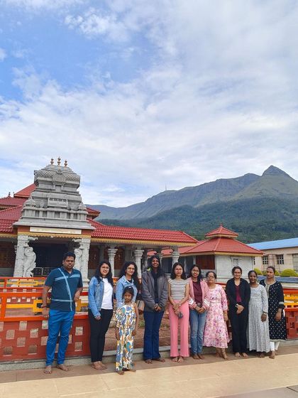 A group photo in front of a temple in Chikmagalur, with the mountains in the background.