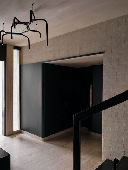 The foyer features dramatic, curved black walls and a sculptural, spider-like chandelier. This entryway sets a moody and sophisticated tone for the rest of the home.
