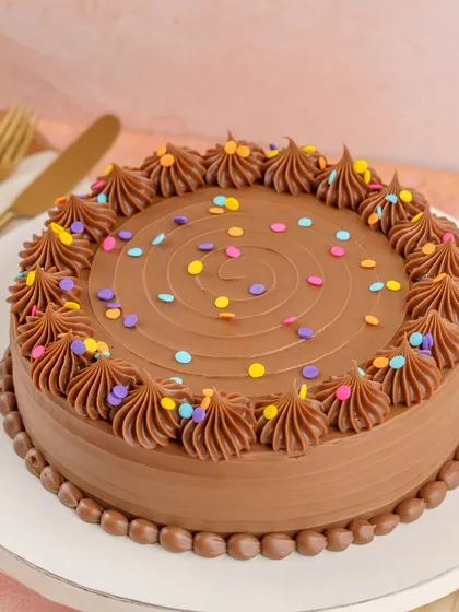 My Milk Chocolate Birthday Cake brings back the magic of childhood. It has a dark chocolate sponge, silky Belgian milk chocolate ganache, and a burst of rainbow confetti.