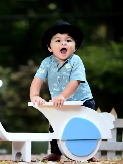 A baby boy having fun on his toy scooter in a park.