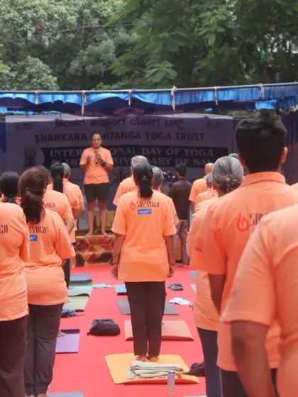 An instructor on stage guiding the large group through poses on International Yoga Day. This highlights the expert instruction provided even in large-scale events.