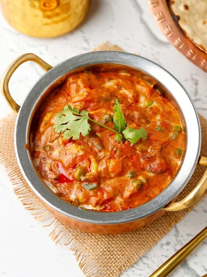 A classic North Indian vegetable curry served in a traditional copper-bottomed kadai, looking rich and creamy.