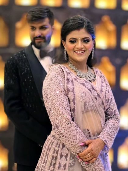 A happy couple at their reception. The bride's pastel lehenga and diamond jewelry are complemented by a soft, elegant makeup look.