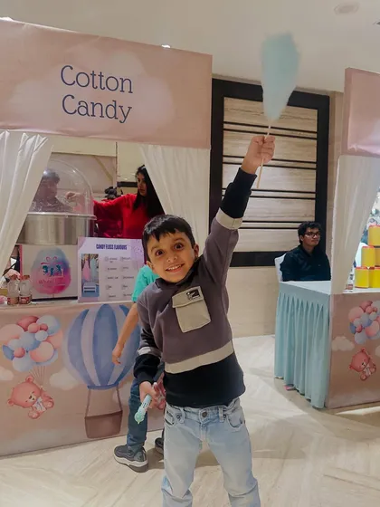 Victory! A young guest proudly holds up his freshly made cotton candy. It's more than just a snack, it's a fun party activity.