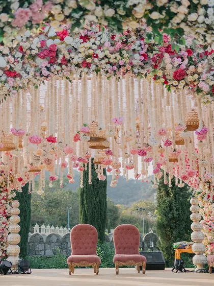 A closer look at a magnificent floral mandap, featuring two regal chairs awaiting the couple. The design incorporates hanging floral strings and birdcages, adding layers of detail and charm to the main ceremony area.