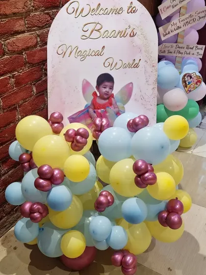 A custom welcome board for "Baani's Magical World," decorated with a small balloon garland.