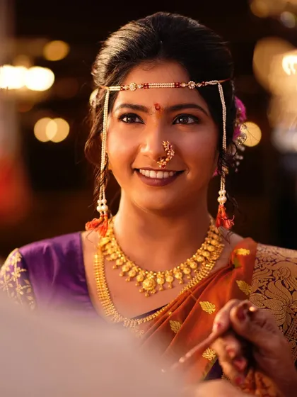 A close-up portrait against a beautifully lit background. The bokeh effect adds a dreamy quality to this shot of the smiling bride.
