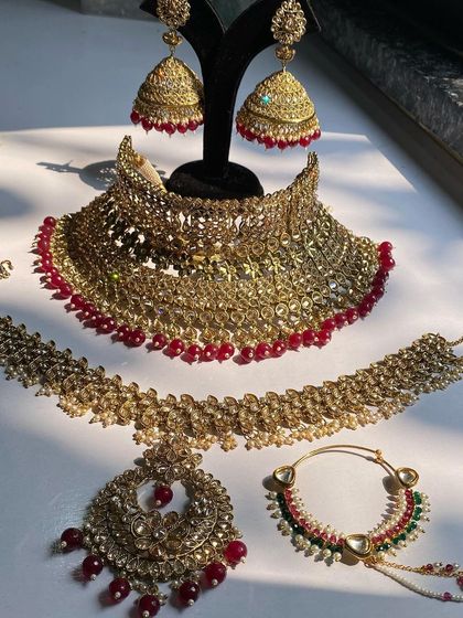 A full display of a classic ruby red bridal set, including the choker, mathapatti, jhumkas, and nath.