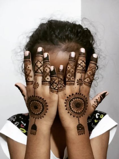 A fun design for a child, featuring a central mandala with a hanging charm and detailed geometric fingers.