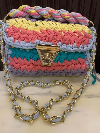 This is the first version of my multi-color crochet bag, featuring a beautiful mix of pastel and bright yarns. The design includes a braided handle and a chain-link strap.