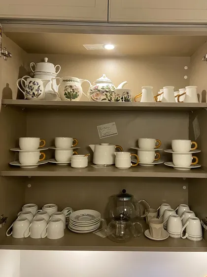 A cabinet dedicated to a beautiful collection of teapots, cups, and saucers. We arranged them by set, creating an elegant display that is ready for high tea.