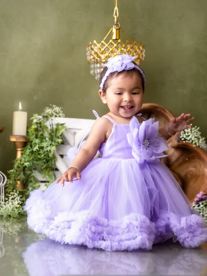 A joyful moment in a lavender dream. The elegant studio setup with candles and florals makes for a magical first birthday portrait.