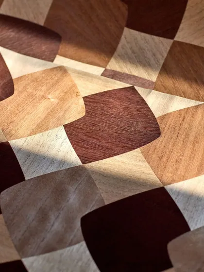 A detailed shot of the hand-laid paulownia wood pieces. The slight variations in color and grain create a striking checkerboard where light and shadow play, telling a story of meticulous craftsmanship.
