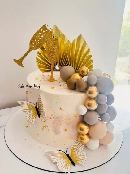 A cocktail party cake with elegant gold fans, butterflies, and a cascade of chocolate spheres.