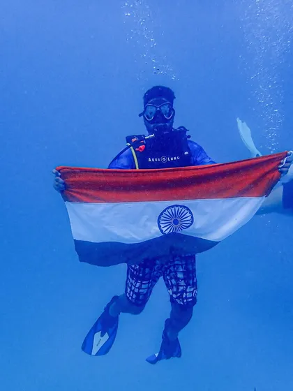 A diver in our group proudly displays the Indian flag underwater to mark the 75th Independence Day, a memorable part of our dive holiday.