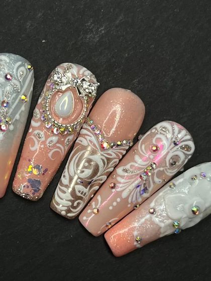 This is an example of a full set of highly detailed press-on nails for a wedding. Each nail is a unique piece of art, featuring ombre, glitter, crystals, and intricate white linework.
