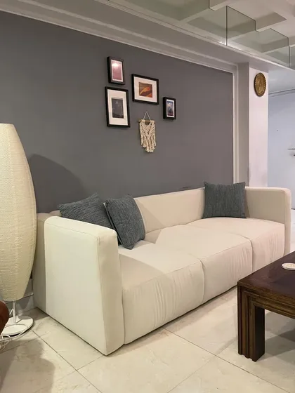 A modern, minimalist block-style sofa in a neutral off-white fabric, shown in a client's home.