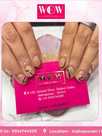 A simple yet graphic design on short, natural nails. This look features a glittery nude base with clean, black abstract lines for a modern and chic feel.