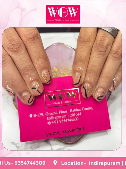 A simple yet graphic design on short, natural nails. This look features a glittery nude base with clean, black abstract lines for a modern and chic feel.
