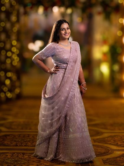 A full-length portrait of the bride in a stunning lavender lehenga. Her confident pose and the beautiful bokeh background create an elegant image.