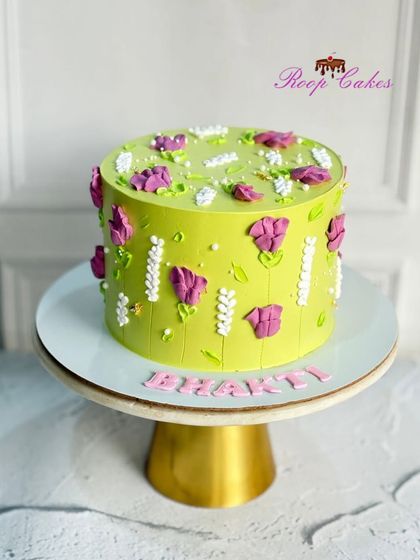 Bursting with color and life, this cake features vibrant green frosting and is decorated with beautiful purple and white flowers created with a palette knife.
