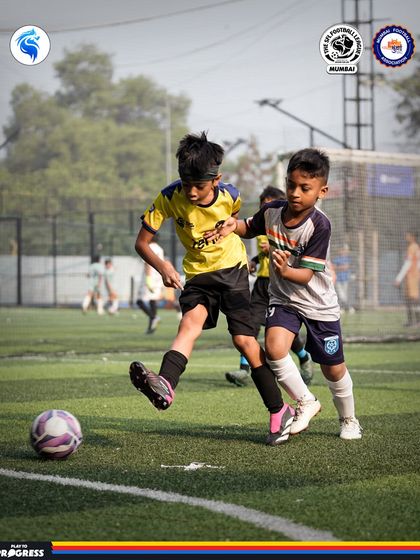 A young player shields the ball from a defender. This image shows the determination and focus taught in our training sessions.