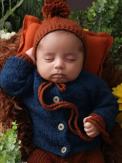 Cozy and cute in a pom-pom hat. The details make the photo. This adorable knitted hat adds texture and personality to the newborn portrait, complementing the natural, rustic theme.