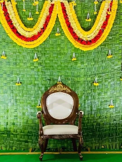 A traditional backdrop made from woven green coconut leaves, decorated with garlands of marigolds. This eco-friendly and classic design is perfect for auspicious occasions.
