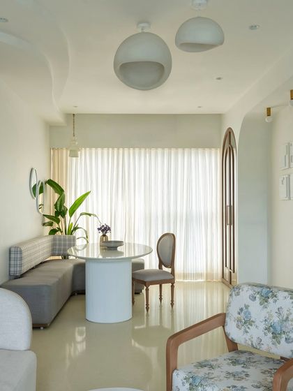 The open layout of this home creates a feeling of spaciousness and light. The dining nook flows seamlessly into the living area, with a cohesive palette of whites, greys, and natural wood tones tying the different zones together.